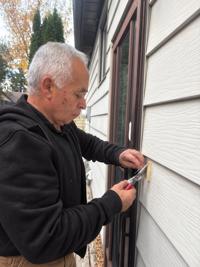 Rocky replacing a doorbell beside an exterior door